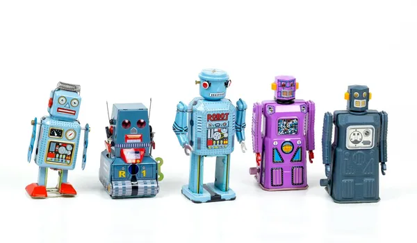 Cztery blaszane roboty zabawki ustawione obok siebie na białym tle.