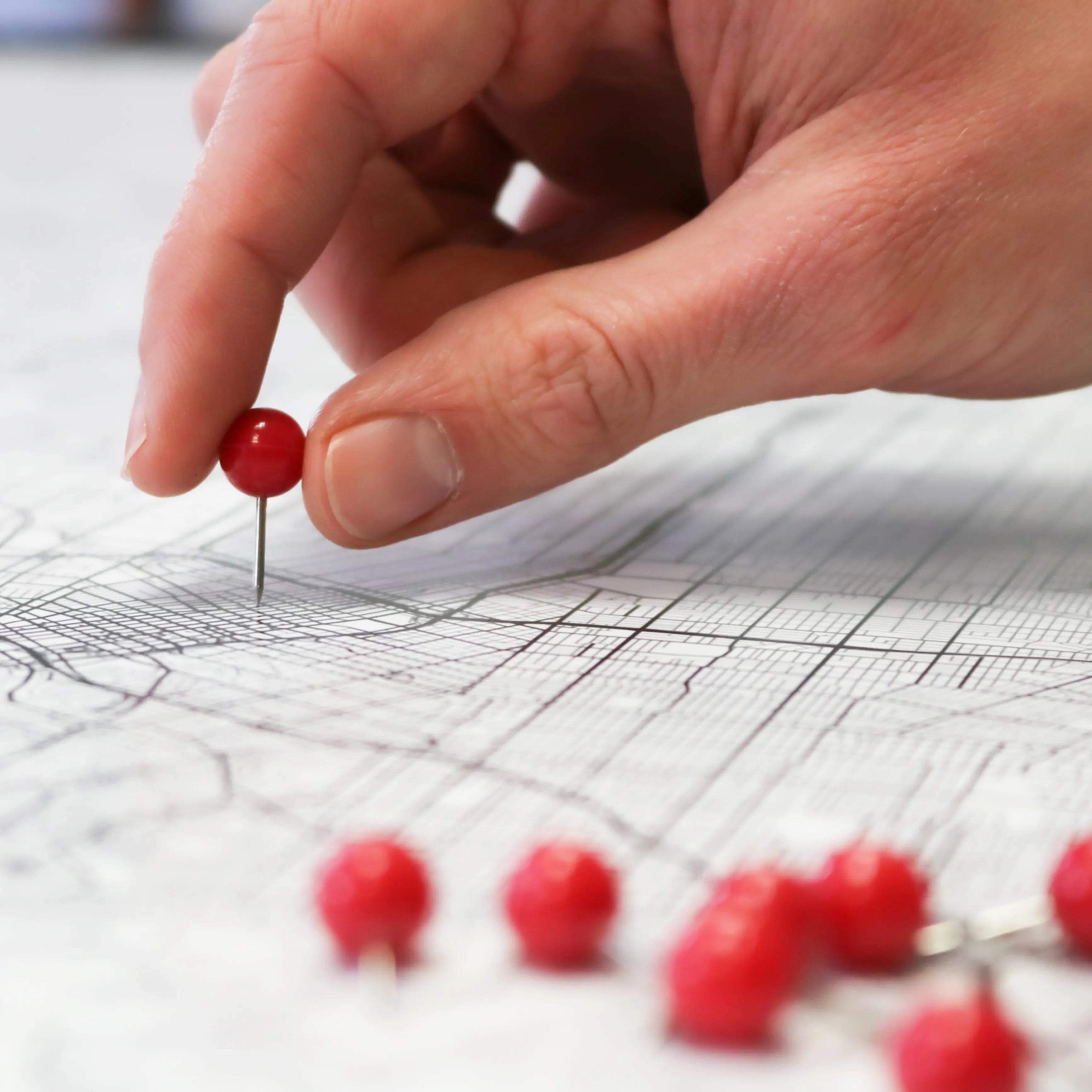 Mapa kartograficzna z przypinanymi do niej czerwonymi pinezkami. Photo by GeoJango Maps on Unsplash.